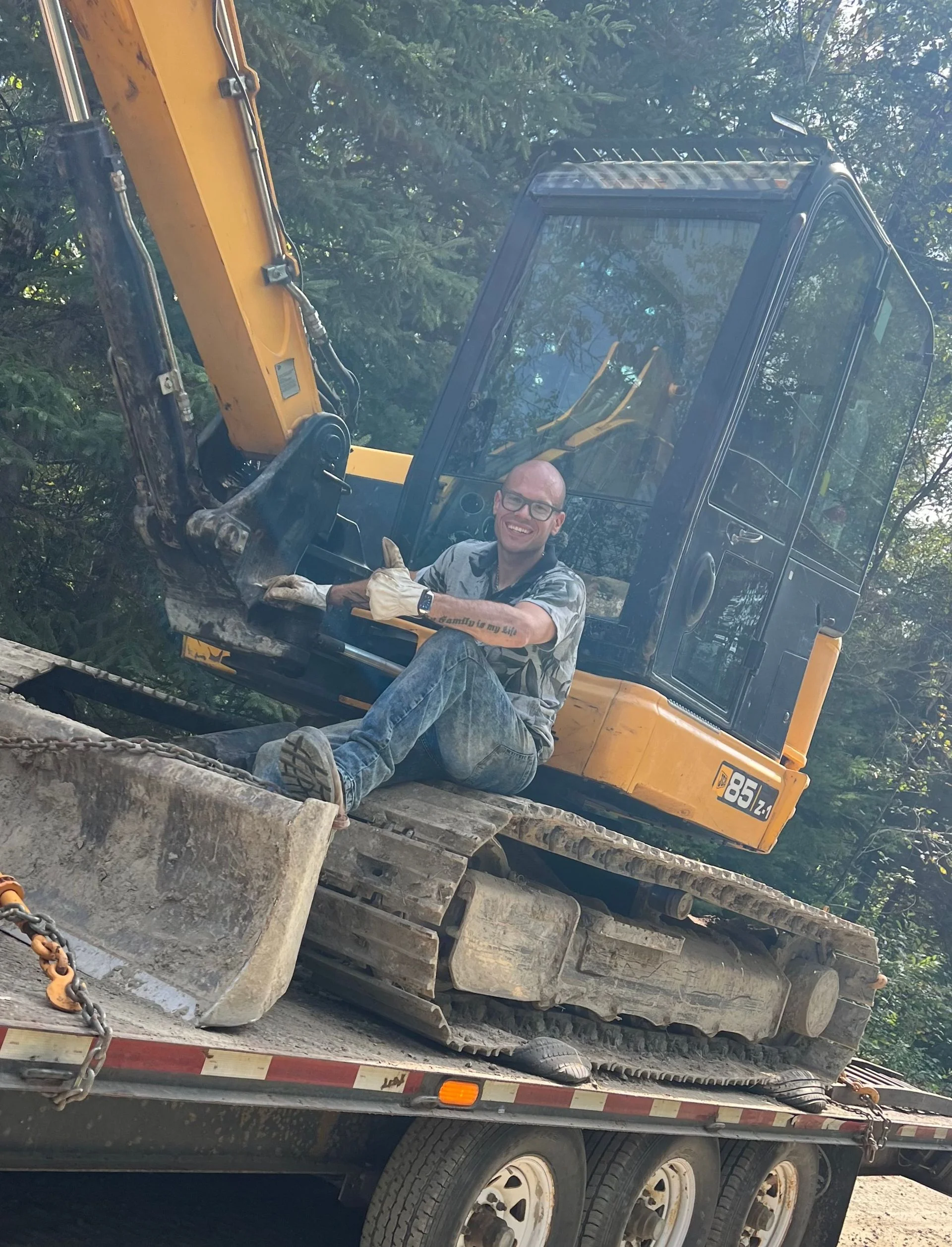 Une personne auprès d’une excavatrice sur le terrain
